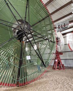 large green windmill positioned beside smaller white windmills for scale.